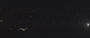 Geceleri havaalanının pistinde yanıp sönen ışıkları olan bir uçak. Arka planda şehir gece lambaları, yavaş çekim Bmpcc 4k.