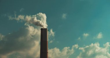 Kömür santralinin bacasından çıkan duman mavi gökyüzüne ve bulutlara karşı, ağır çekimde, Bmpcc 4k. Kötü ekoloji, çevre ve atmosfer kirliliği, endüstrilerin küresel ısınma üzerindeki etkisi