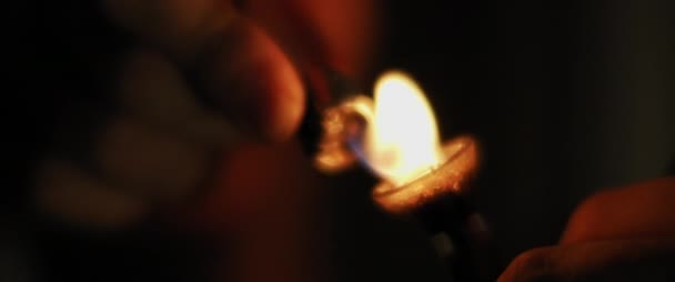 Une personne allume un bong en verre d'herbe, le processus de fumer de la marijuana médicale. Chambre sombre la nuit, gros plan, faible profondeur de champ, beau bokeh, prise de vue cinématique avec BMPCC 4K 