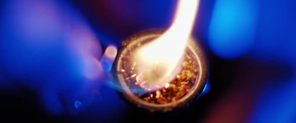 Gros plan cinématographique, brûlure de cannabis, le processus de fumer de l'herbe à partir d'un bong, au ralenti, éclairage de la pièce bleu foncé, faible profondeur de champ, beau bokeh. BMPCC 4K 