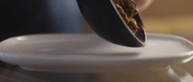 Beyaz bir plakaya yayılan kenevir tomurcuklarını kapatın, sığ alan derinliği, yavaş çekim, Bmpcc 4k. Marihuana, ot, sigara konsepti. Cbd, Thc görüntüleri