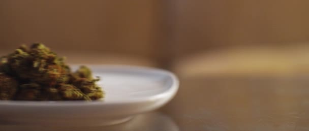 大麻の芽を持つプレートはテーブルの上で移動し フィールドの浅い深さを閉じます Bmpcc マリファナ 喫煙薬の概念 Cbd Thcの映像 — ストック動画