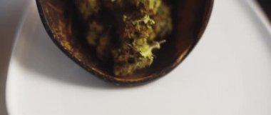 Beyaz bir plakaya yayılan kenevir tomurcuklarını kapatın, sığ alan derinliği, yavaş çekim, Bmpcc 4k. Marihuana, ot, sigara konsepti. Cbd, Thc görüntüleri