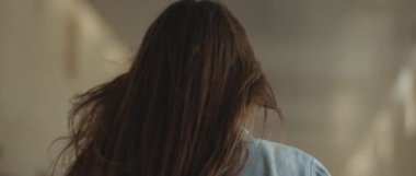 Rüzgarlı, uzun kahverengi saçlı ve kot gömlekli bir kadın havaalanında turkuaz bavuluyla yürüyor. Slow Motion, sinematik çekim. Bmpcc 4k.