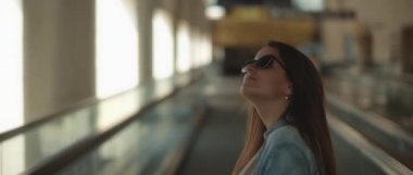 Güneş gözlüklü ve kot gömlekli bir kadın rüzgar saçı dalgalı bir yolda dikilirken etrafına bakıyor. Seyahat ediyorum. Yavaş çekim sinematik çekim. Bmpcc 4k 