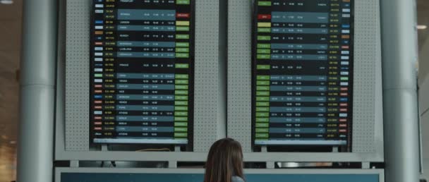 Frau Schaut Auf Die Anzeigetafel Des Flughafens Und Sucht Nach — Stockvideo