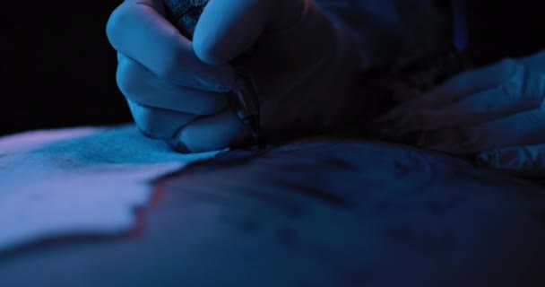 Zbliżenie Tatuażysty Robiącego Komuś Tatuaż Niebieskie Oświetlenie Studyjne Płytka Głębokość — Wideo stockowe