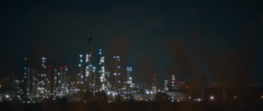 Power plant, factory with lights lit up at night, bokeh, selective focus. Bad ecology, environment and atmosphere pollution. Smoke industries influence on global warming and climate change. BMPCC 4K