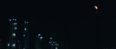 Fire burning at the top of chimney tower at power plant at night,slow motion,BMPCC 4K.Bad ecology,environment and atmosphere pollution.Smoke industries influence on global warming and climate change