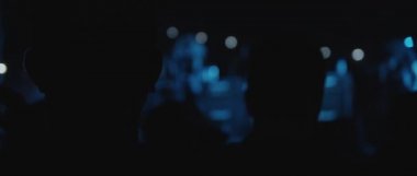 Behind shot of people silhouettes during a live show concert of a band, in a night club. blue lighting. Close up, behind shot, handheld, slow motion. BMPCC 4K 