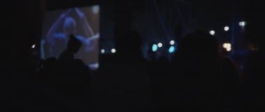 Behind shot of people silhouettes during a live show concert of a band, in a night club. blue lighting. Close up, behind shot, handheld, slow motion. BMPCC 4K 