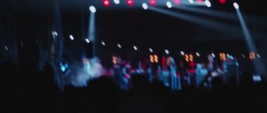 Behind shot of people crowd in front of a stage during a live show concert or a night club, light show at the background. Medium, back shot, slow motion. BMPCC 4K