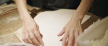 Chef getting pizza dough ready on a wooden surface in kitchen of restauarant. Slow Motion, close up 4K footage. Shot with Blackmagic Design Pocket Camera.