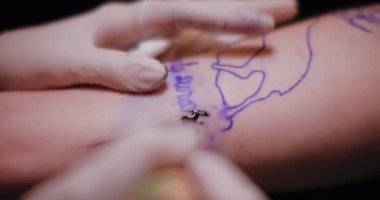 Dövmeci bir insanın eline mesaj dövme çiziyor. Yaklaş, yavaş çekim, alanın derinliği. BMPCC 4K