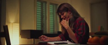 Genç bir kadın, üniversite öğrencisi masasında oturuyor, akşamları evde ders çalışıyor, matematik hesaplıyor ve defterine notlar yazıyor. Ağır çekim. BMPCC 4K