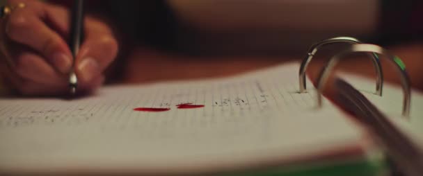 Gros plan du sang qui coule sur le carnet pendant que le jeune étudiant étudie à la maison. Concept d'horreur. Profondeur de champ faible. BMPCC 4K 