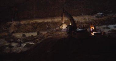 Kazıcı gece inşaat alanında kazı yapıyor. Yavaş çekim, endüstriyel ekipman konsepti. BMPCC 4K