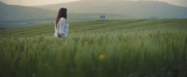 Klasik kameralı genç bir kız gün batımında buğday tarlasında yürüyor, doğanın ve manzaranın tadını çıkarıyor. Uzun atış, yavaş hareket, kısa namlulu Dof. Macera, yaşam tarzı konsepti. BMPCC 4K 