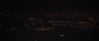 Geceleri uçak penceresinden şehrin havadan görünüşü. Gece vakti yollar ve binalar üzerinde uçan bir uçak. Macera, seyahat, seyahat konsepti. Yavaş Hareket, BMPCC 4K. 