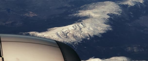 飛行機は雪の山の上を飛ぶ 飛行機の窓から見る 旅のコンセプト スローモーション Bmpcc — ストック動画