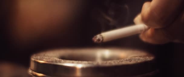 Femme dépose de la cendre d'une cigarette dans le cendrier, beau brin de fumée. Fumer, concept malsain. CLOSE, MOTION LENTE, SHALLOW DOF, BMPCC 4K . 