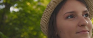 Şapkalı, sırıtan, gün batımında mutlu hisseden genç bir kadına yaklaş. Yaşam tarzı, doğa, insan konsepti. Yavaş Hareket, ŞALLOW Dof, BMPCC 4K