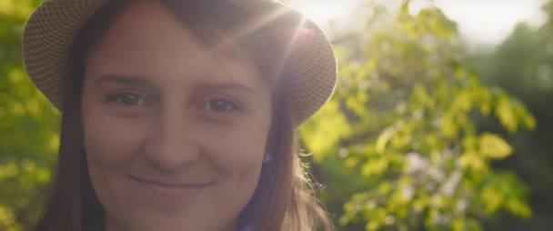 帽子をカメラを見て若い女性の肖像画は 笑みを浮かべて 日没時に外で幸せを感じる ライフスタイル 人々の概念 スローモーション シャロードーフ Bmpcc — ストック動画