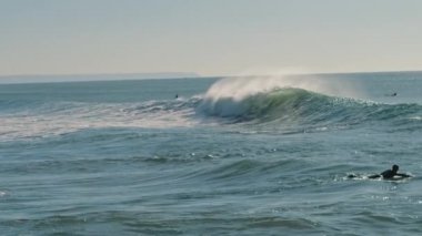 Güneşli bir günde büyük bir okyanus dalgası kıyıya doğru koşar. Ağır çekim, BMPCC 4K.