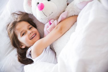 güzel küçük kız yatakta onun oyuncak ayı sarılma