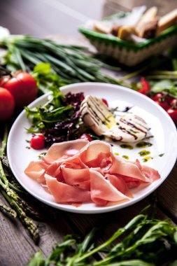 İştah açıcı yemek et ve peynir ahşap arka plan üzerinde yeşillikleri ile