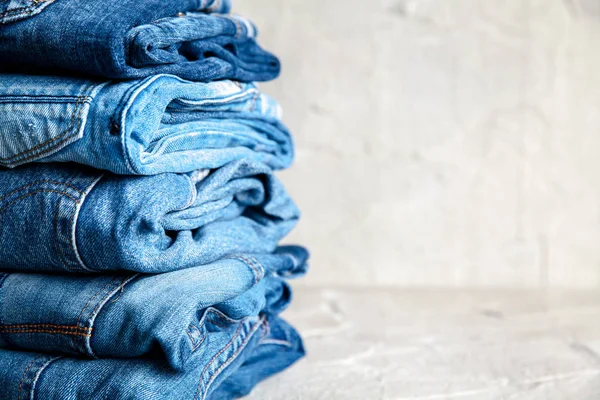 Stack of blue jeans on a gray background — Stock Photo, Image