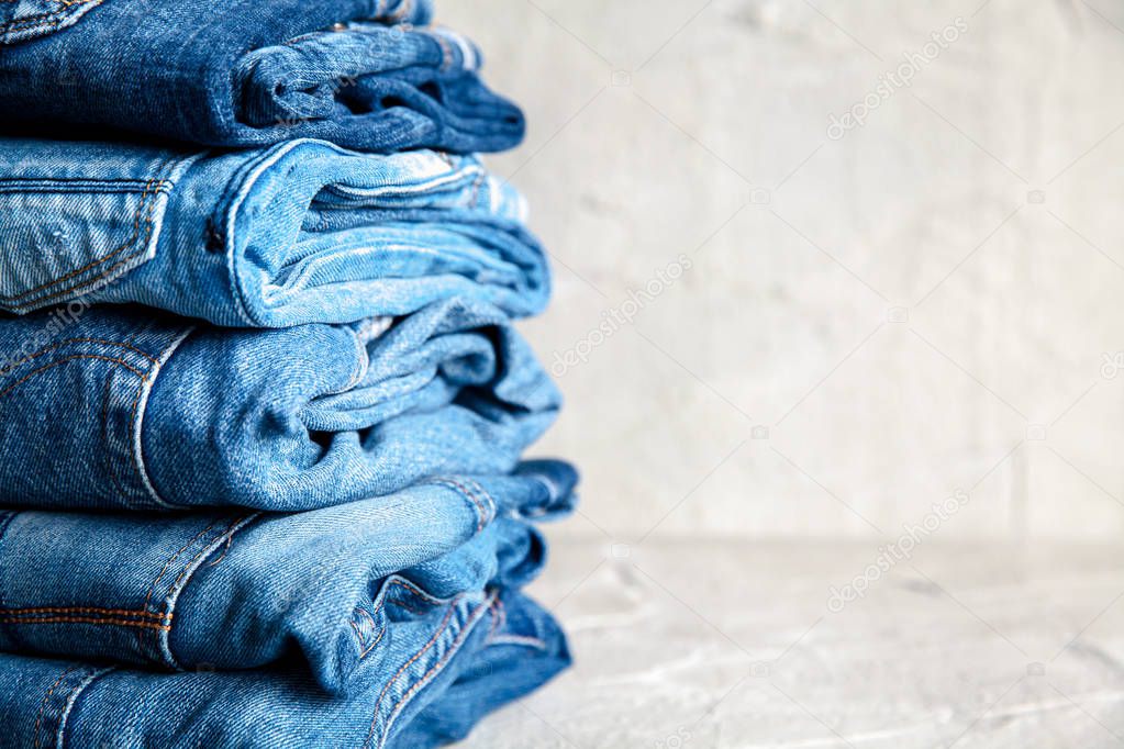 stack of blue jeans on a gray background