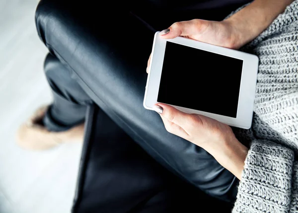 Bir tablet elinde, okuyucu ile güzel manikür tutan bir kız. Deri pantolon, ugg botlar. Moda, Stil, öğrenme, modern, eğlence