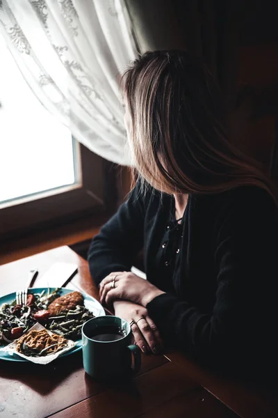 Une jeune femme assise dans le restaurant, regardant par la fenêtre. Délicieux mets et vin . — Photo