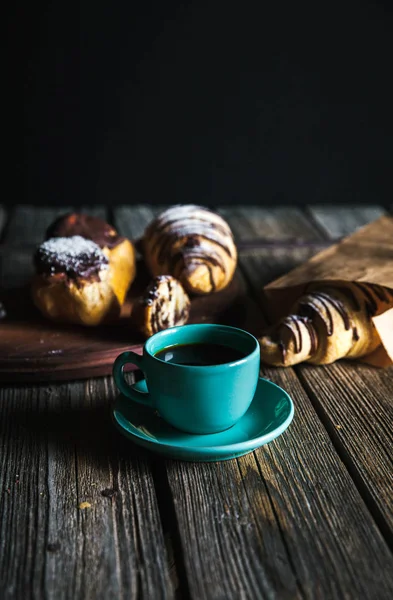 Croissant och vit kopp svart kaffe på brun duk. — Stockfoto
