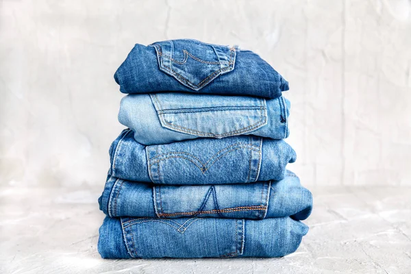 Stack of blue jeans on a gray background — Stock Photo, Image