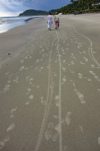 Άνθρωποι περπατούν στην παραλία με τη δύση του ηλίου — Φωτογραφία Αρχείου