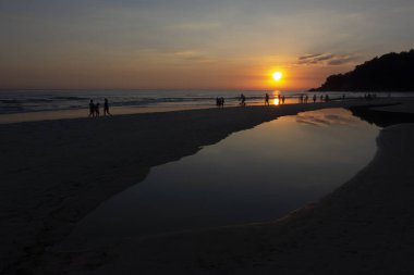 Gün batımında plajda insan aktiviteleri.
