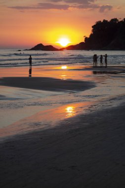 Gün batımında plajda insan aktiviteleri.