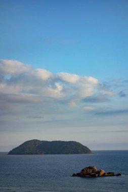 Arkasında bir kaya ve bir ada olan deniz burnu.