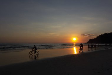 Gün batımında plajda insan aktiviteleri