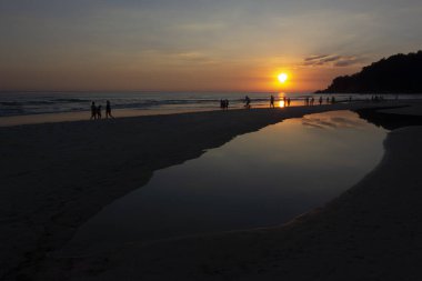 Gün batımında plajda insan aktiviteleri