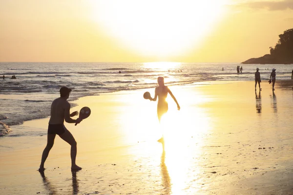 Gente jugando en la playa al atardecer — Foto de Stock