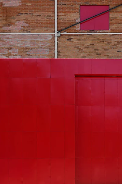 Detalhes da arquitetura do contraste, parede velha do tijolo, porta vermelha grande — Fotografia de Stock