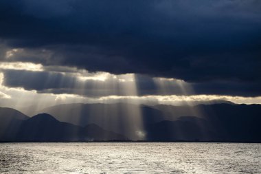 Fırtınadan sonra ışık ışınları karanlık bulutların arasından geçer.