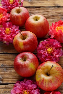 Güzel çiçeklerle çevrili ahşap bir arka planda olgun elmalar.