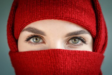 Beautiful eyes of a girl. A person covers a red scarf with a scarf. Burqa, hijab, niqab, chadra.