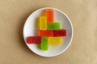 Seramik bir tabakta eski ve pürüzlü kağıt üzerinde reçelli şekerler. Yukarıdan görüntüle.