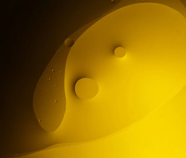 Drops of oil in water on a yellow background. Beautiful abstract background.