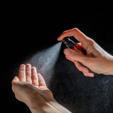 Kadının elleri virüse karşı antiseptik püskürtüyor. Salgın Covid-19.